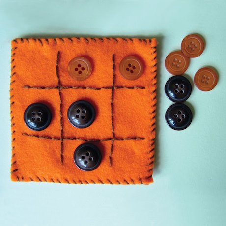 Photo of a felt tic tak toe board with hand stiching around the edges and to create the vertical and horizontal used to create the play squares. Two different colored sets of buttons are used to be the playing pieces.